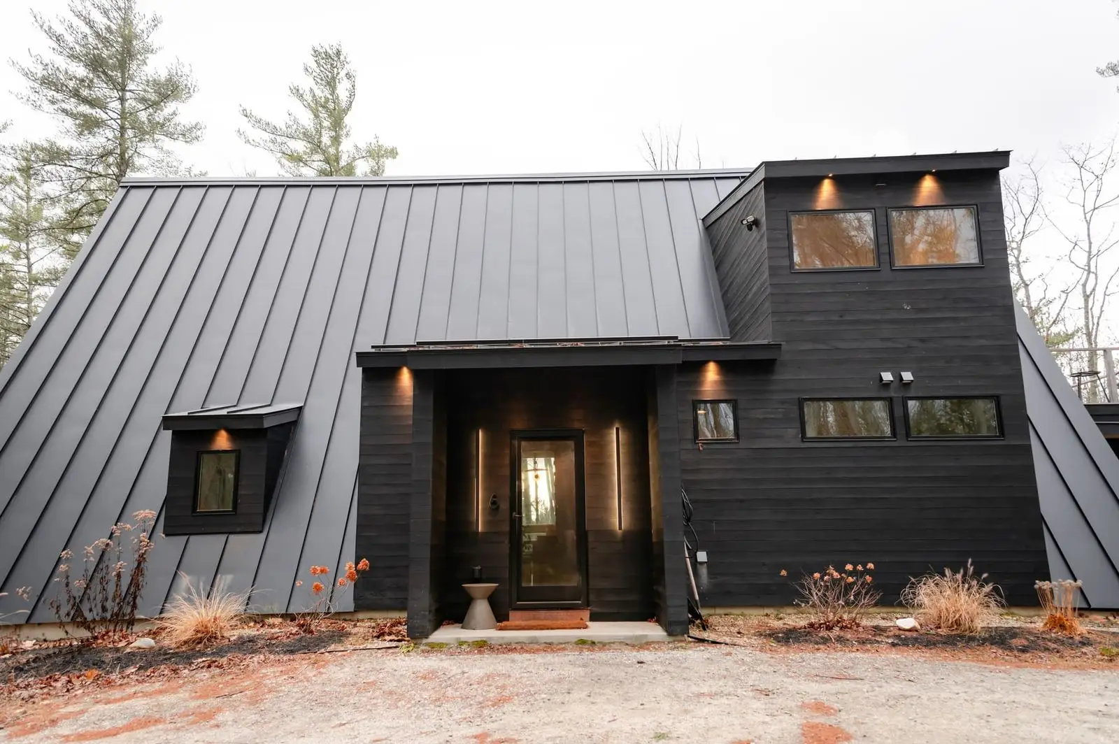 Modern house with a dark metal roof and warm lights at dusk